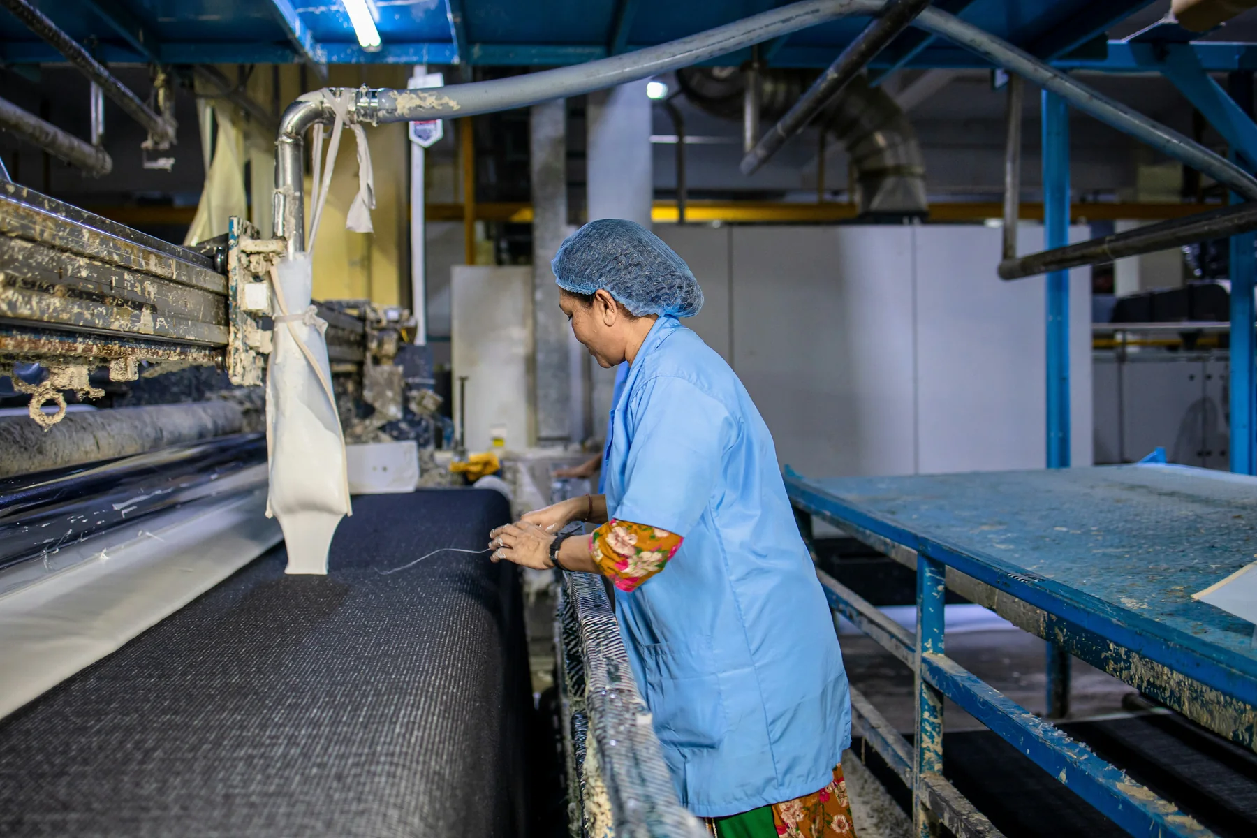 Textile worker inspecting fabric at production equipment