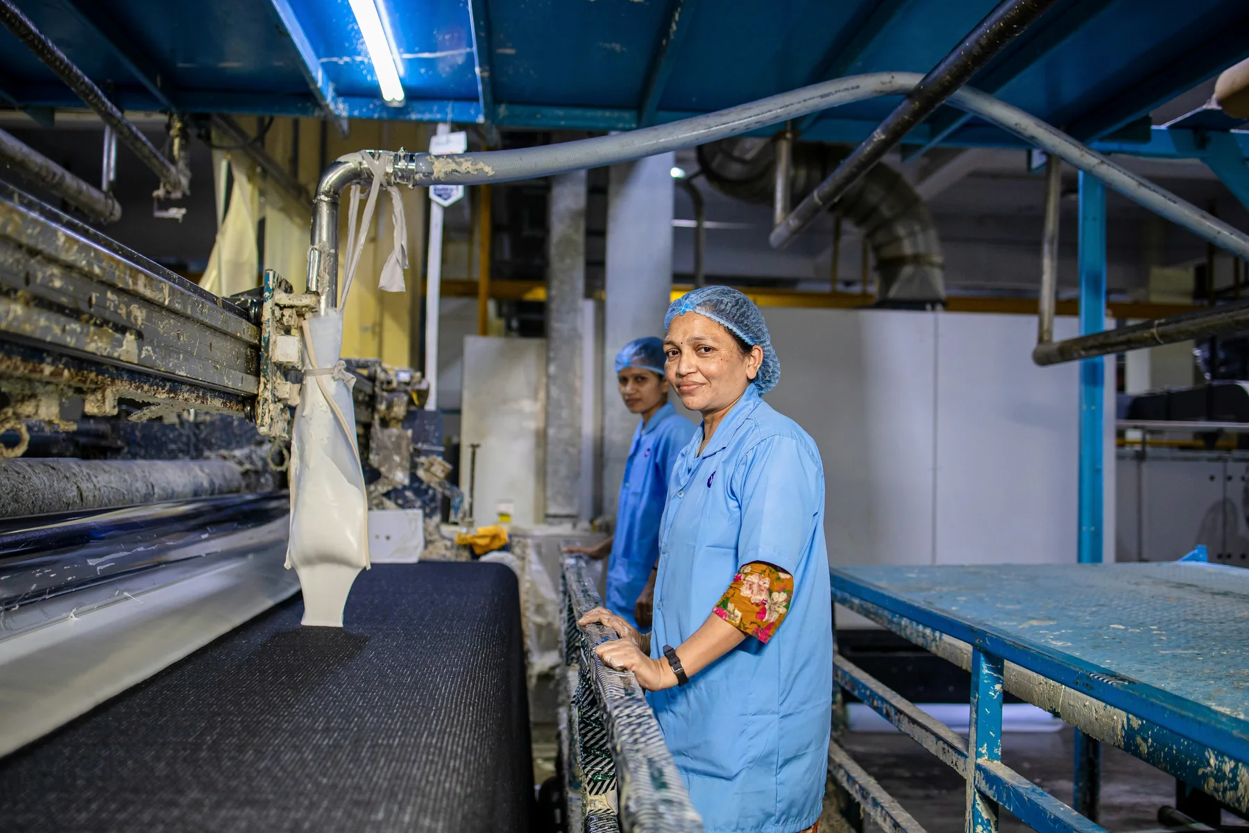 Textile production team working beside industrial machinery